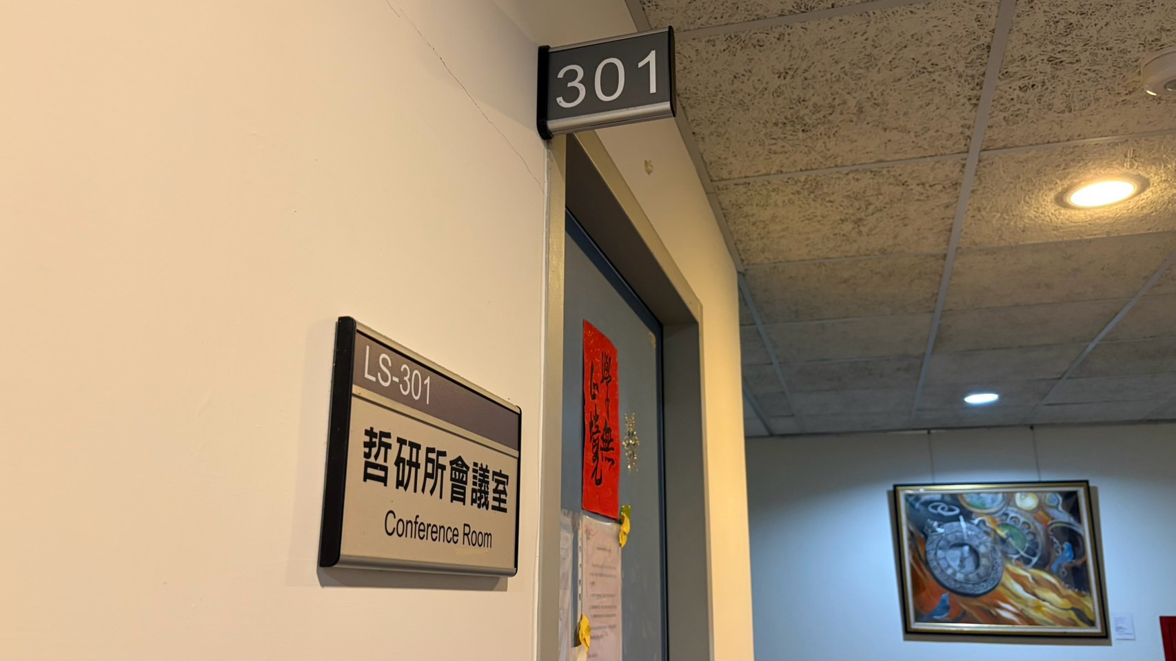 LS-301 門口，門旁牆上掛著「哲研所會議室 Conference Room」門牌，門框上方是 301 號房號燈箱。