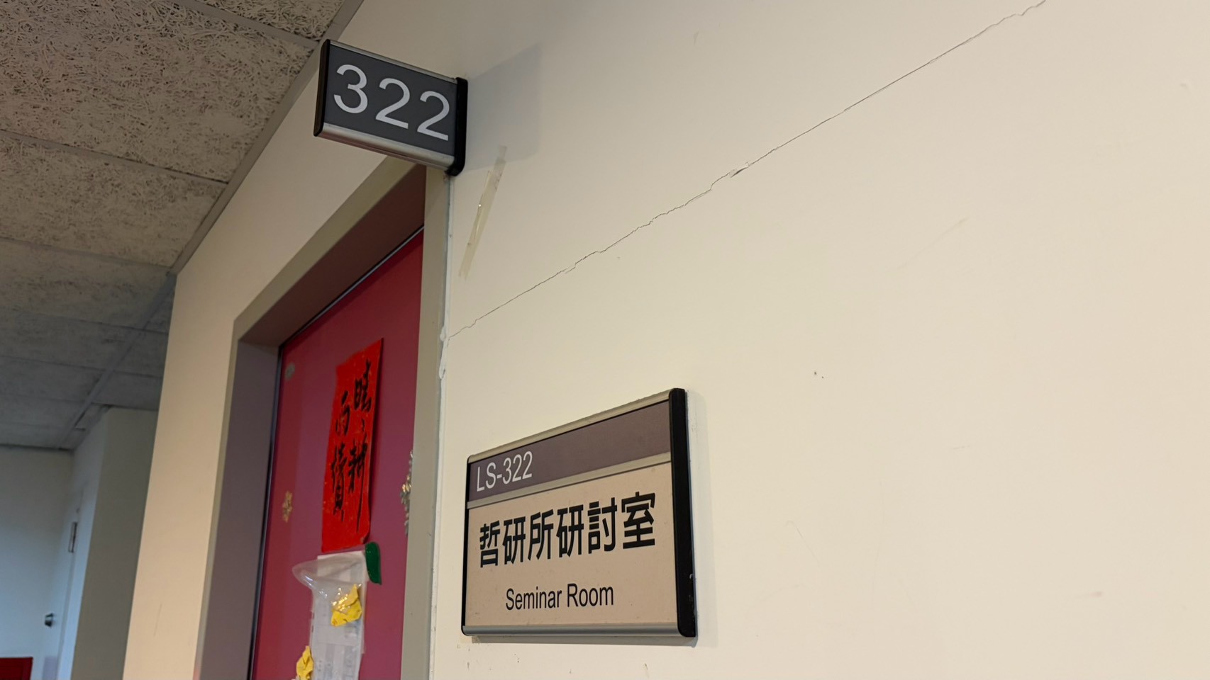 LS-322 門牌特寫，牌面寫著「哲研所研討室 Seminar Room」，門框上方是 322 號房號燈箱。